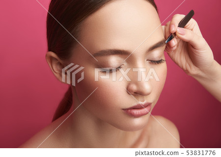 Beautician plucking young lady eyebrows with tweezers Beautician plucking young lady eyebrows with tweezers 53831776