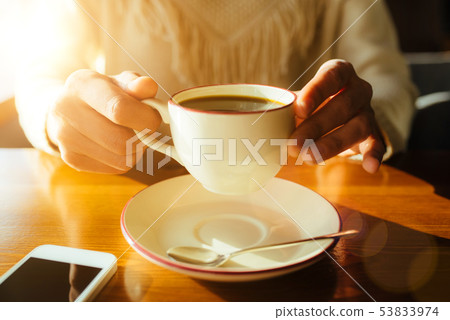 Woman holding in hands cup of coffee on wooden background 53833974