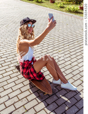 A skateboard girl, summer city, takes selfie of herself, online call to Internet. Happy smiling A skateboard girl, summer city, takes selfie of herself, online call to Internet. Happy smiling 53834320