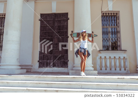 Girl skateboard, summer city, posing background of columns of door and window. Free space for text Girl skateboard, summer city, posing background of columns of door and window. Free space for text 53834322