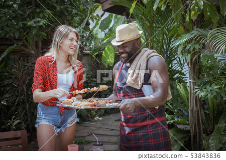 Smiling chef give barbecue to female friend for 53843836