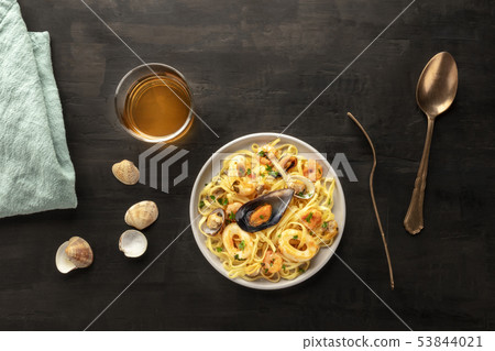Seafood pasta. Tagliolini with mussels, shrimps, clams and squid rings, with a glass of white wine Seafood pasta. Tagliolini with mussels, shrimps, clams and squid rings, with a glass of white wine 53844021