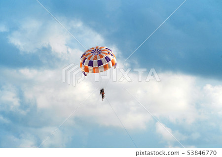 People flying in a colorful parachute or parasail 53846770