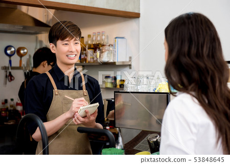 Young coffee shop owner taking order from customer Young coffee shop owner taking order from customer 53848645