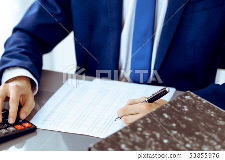 Bookkeeper or financial inspector hands making report, calculating or checking balance. Internal Bookkeeper or financial inspector hands making report, calculating or checking balance. Internal 53855976