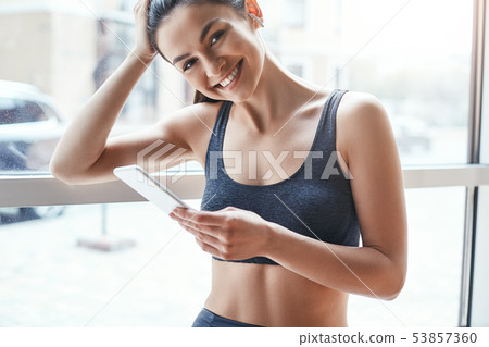 Simply happy. Beautiful and cheerful woman in sportswear and headphones listening music and looking Simply happy. Beautiful and cheerful woman in sportswear and headphones listening music and looking 53857360