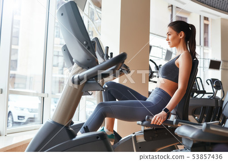 Exercising. Side view of young beautiful woman with perfect body in sportswear and smart watch on 53857436