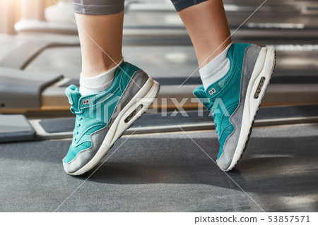 Comfort in everything. Close-up photo of woman foot in blue stylish sneakers standing on a treadmill Comfort in everything. Close-up photo of woman foot in blue stylish sneakers standing on a treadmill 53857571