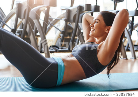 Fitness exercise. Strong and sporty young woman in sportswear is doing exercise for perfect press at 53857684