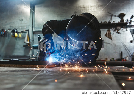 Weld Done Well. Man welds at the factory 53857997