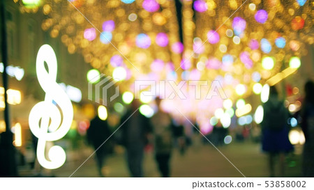 Blurred people walk along illuminated pedestrian street in the evening 53858002