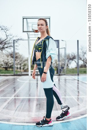 Believe in yourself. Young and strong disabled woman in sportswear is standing on stadium and 53858350
