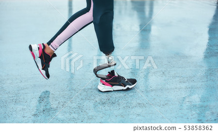 Disabled athlete. Cropped image of female legs with prosthesis walking outdoors Disabled athlete. Cropped image of female legs with prosthesis walking outdoors 53858362