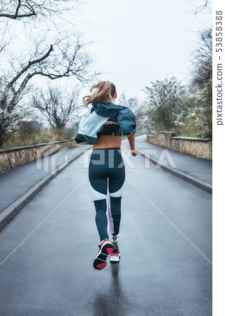You can do it Back view of strong disabled woman with bionic leg in sportswear is running outdoors 53858388