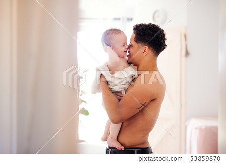 Father and small toddler son wrapped in towel in a bathroom indoors at home. Father and small toddler son wrapped in towel in a bathroom indoors at home. 53859870