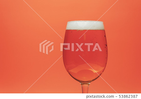 Beer of glass on a coral orange background. Beer of glass on a coral orange background. 53862387