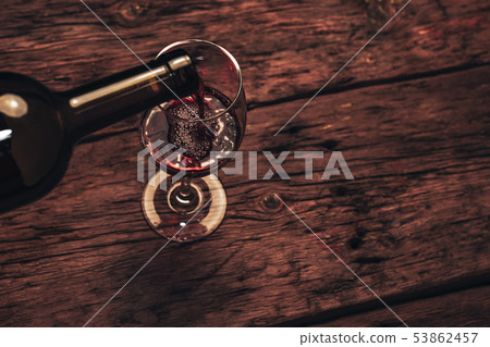 Pouring Red wine bottle and glass of wine  on a 53862457