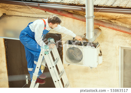HVAC technician working on a capacitor part for condensing unit HVAC technician working on a capacitor part for condensing unit 53863517