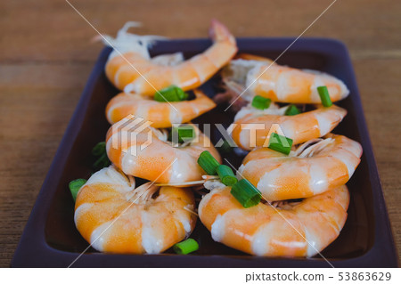 Steamed white shrimp in dish on wood background. 53863629