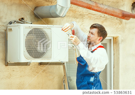 HVAC technician working on a capacitor part for condensing unit HVAC technician working on a capacitor part for condensing unit 53863631