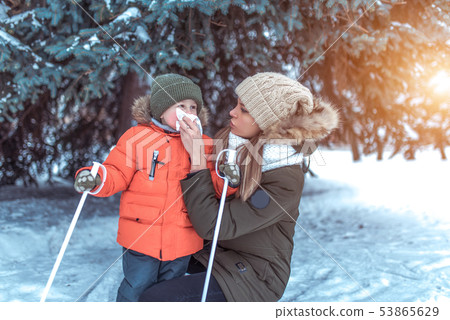 A woman mom wipes her nose with handkerchief, snot napkin small child, caring child during cold 53865629