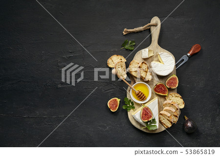 Two glasses of red wine and cheese plate with fruit on the black stone Two glasses of red wine and cheese plate with fruit on the black stone 53865819