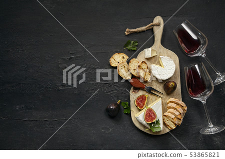 Two glasses of red wine and cheese plate with fruit on the black stone Two glasses of red wine and cheese plate with fruit on the black stone 53865821