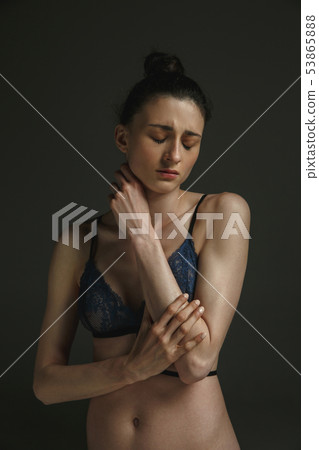 Half-length portrait of young sad woman on dark studio background Half-length portrait of young sad woman on dark studio background 53865888