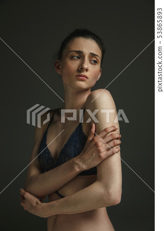 Half-length portrait of young sad woman on dark studio background 53865893