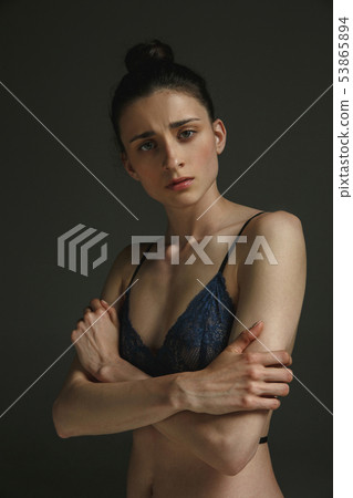 Half-length portrait of young sad woman on dark studio background Half-length portrait of young sad woman on dark studio background 53865894
