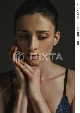Half-length portrait of young sad woman on dark studio background Half-length portrait of young sad woman on dark studio background 53865897