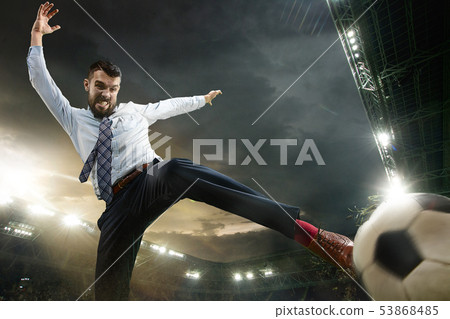 Office man as a soccer or football player at the stadium 53868485