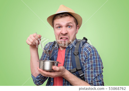 Man tourist in summer hat taste a strange meal 53868762