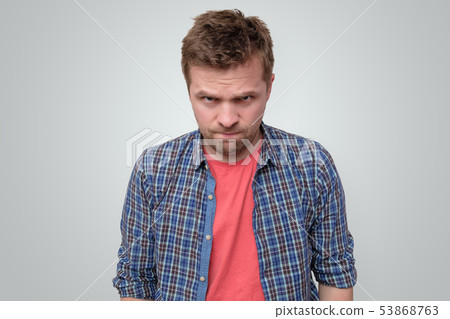 Angry young man looking at camera frowning 53868763