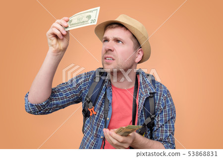 Tourist in hat holds dollar bank note checking it Tourist in hat holds dollar bank note checking it 53868831