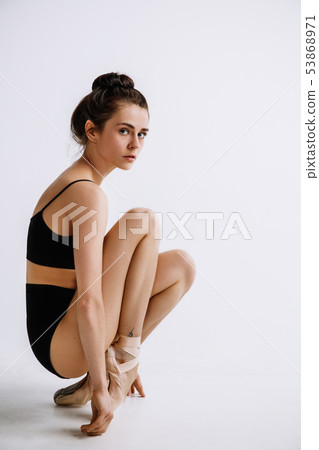 Young female ballet dancer against white studio background 53868971