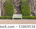 Elegant wooden white bench by trimmed green hedge 53869538