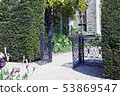 garden open black iron gate between trimmed hedge 53869547