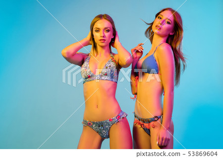 Beautiful girls isolated on blue studio background in neon light Beautiful girls isolated on blue studio background in neon light 53869604