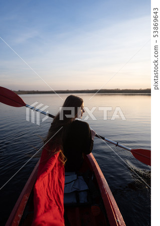 Back view of happy cute girl holding paddle in a kayak on the river 53869643