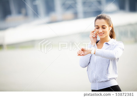 Sports woman doing exercises and listening to music in the urban environment Sports woman doing exercises and listening to music in the urban environment 53872381