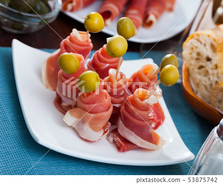 Traditional Spanish tapas - rolls of jamon serrano served with green olives Traditional Spanish tapas - rolls of jamon serrano served with green olives 53875742