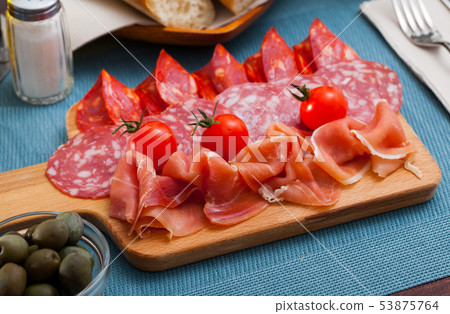 Spanish tasty meal slicing sausages and jamon with tomatoes, close up Spanish tasty meal slicing sausages and jamon with tomatoes, close up 53875764