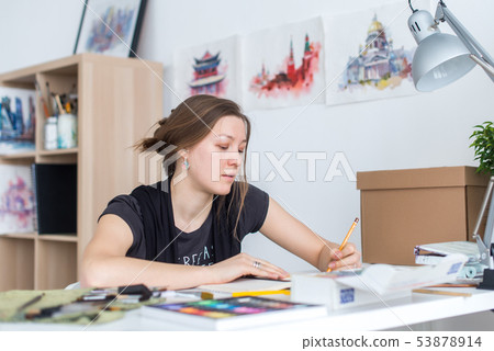 Young female artist drawing sketch using sketchbook with pencil at her workplace in studio. Side 53878914