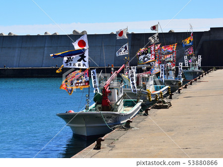 At the boat festival, several fishing boats decorated with colorful big fishing flags are moored in a row at the fishing port. At the boat festival, several fishing boats decorated with colorful big fishing flags are moored in a row at the fishing port. 53880866