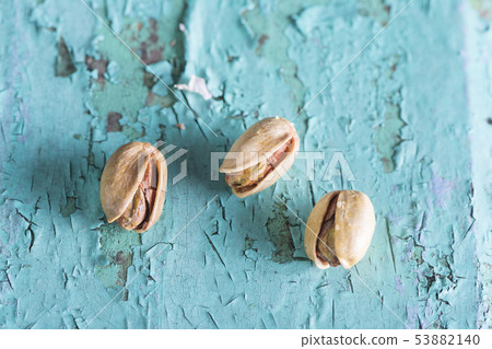 Three pistachios on turquoise wooden plank 53882140