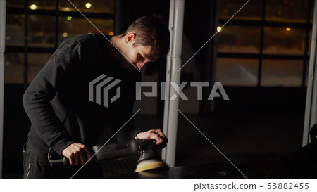 Car detailing - Hands with orbital polisher in auto repair shop. Polished black car. Car detailing - Hands with orbital polisher in auto repair shop. Polished black car. 53882455