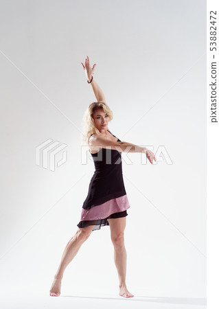 Photo of long-haired blonde looking to side with raised arms dancing in empty studio Photo of long-haired blonde looking to side with raised arms dancing in empty studio 53882472