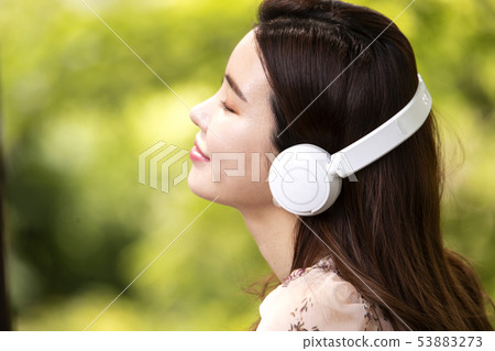 A woman wearing headphones and listening to music A woman wearing headphones and listening to music 53883273