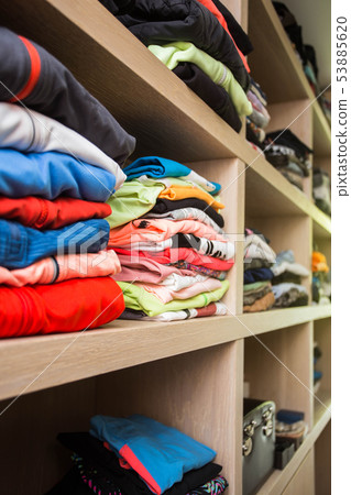 Open wardrobe with lots of folded clothes 53885620